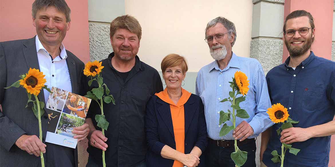 Fünf Menschen mit Sonnenblumen und Urkunde sind zu sehen