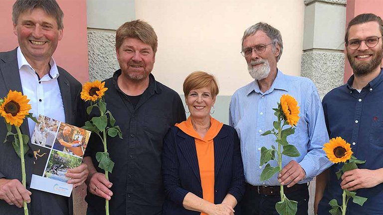 Fünf Menschen mit Sonnenblumen sind auf dem Foto zu sehen