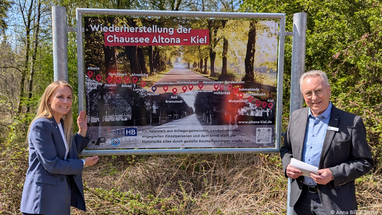 Staatssekretärin Carstens und SHHB-Präsident Peter Stoltenberg vor Schild