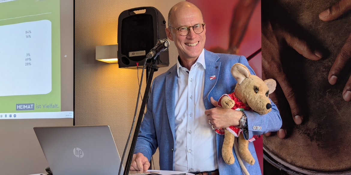 Mann mit Mäusekuscheltier bei Vortrag