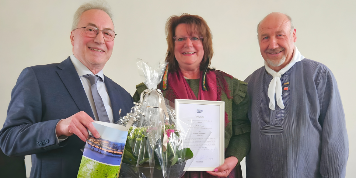 Drei Personen, eine mit Urkunde