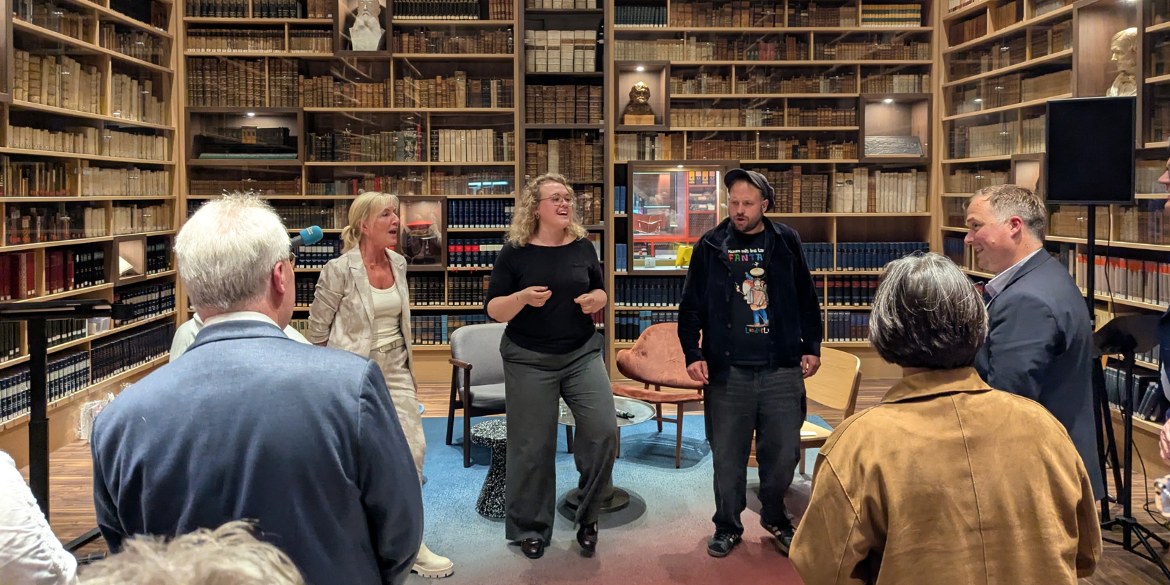 Drei Personen auf Bühne in Bibliothek