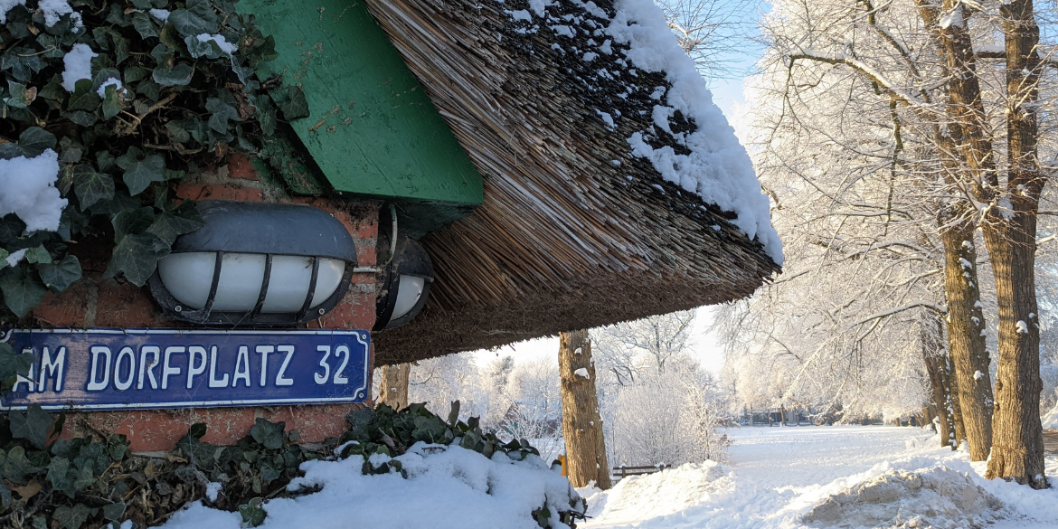 Hausecke, dahinter Dorfplatz im Tiefschnee
