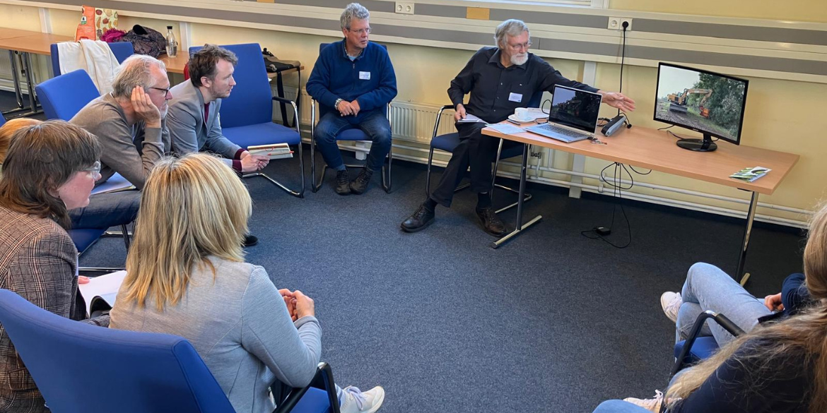 Workshop-Teilnehmende sitzen im Kreis um einen Bildschirm