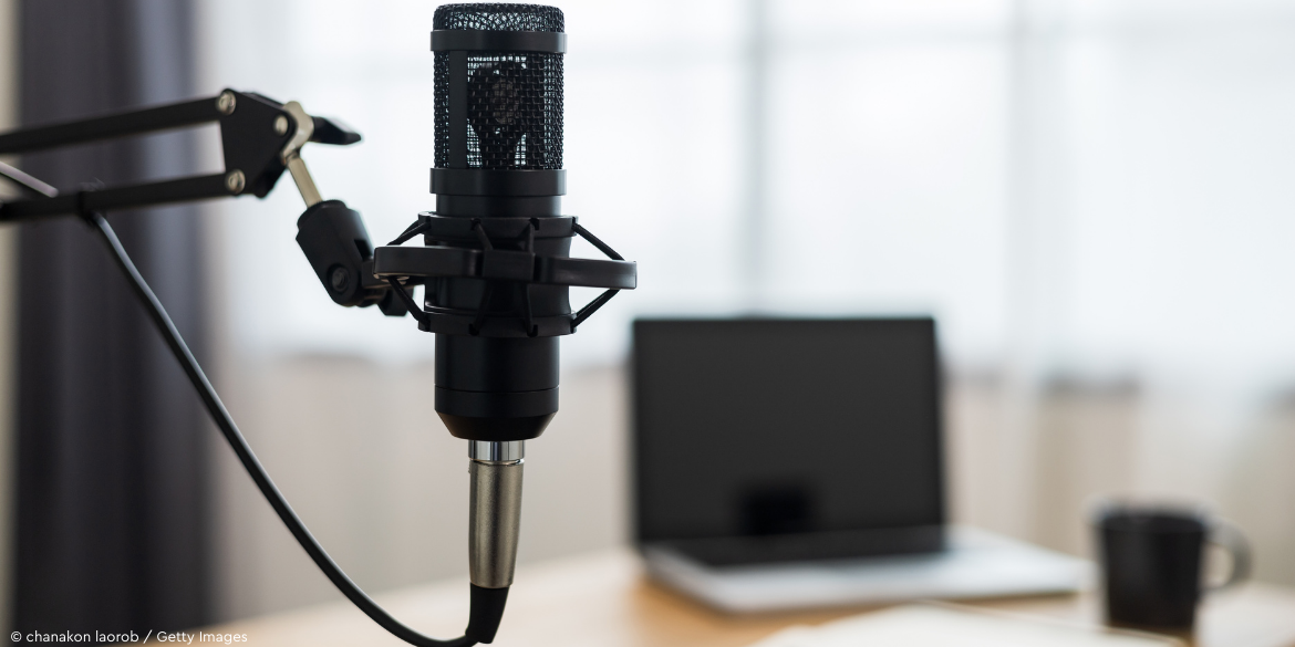 Tisch mit Mikrofon, Laptop und Kaffeetasse