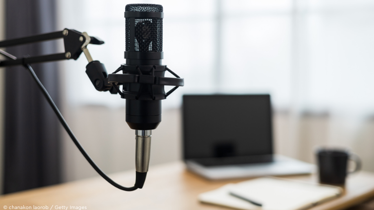 Tisch mit Mikrofon, Laptop und Kaffeetasse