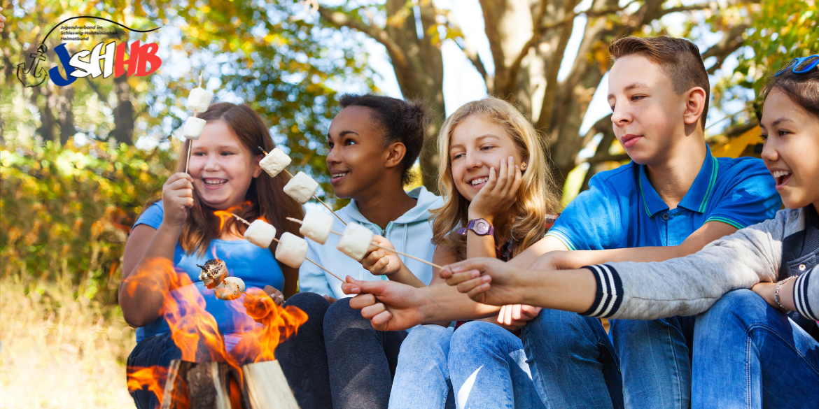 Jugendliche sitzen am Lagerfeuer und rösten Marshmallows © SerrNovik
